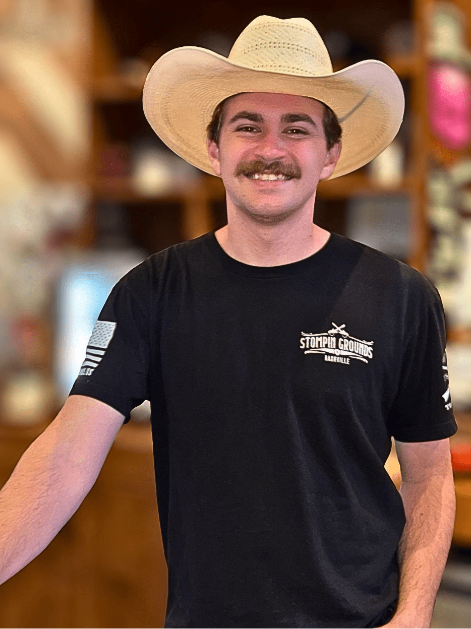 Screenshot 2025-08-06 at 13.40.43 Person with mustache in cowboy hat smiling, wearing black shirt indoors.