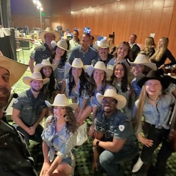 Group of people wearing cowboy hats and denim shirts posing indoors.