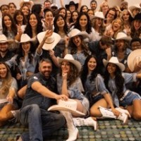 Group of people in cowboy hats posing happily indoors.