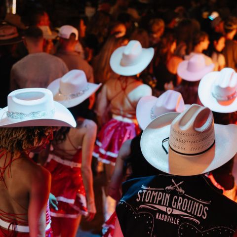 Group of people in cowboy hats and red outfits at a crowded event.