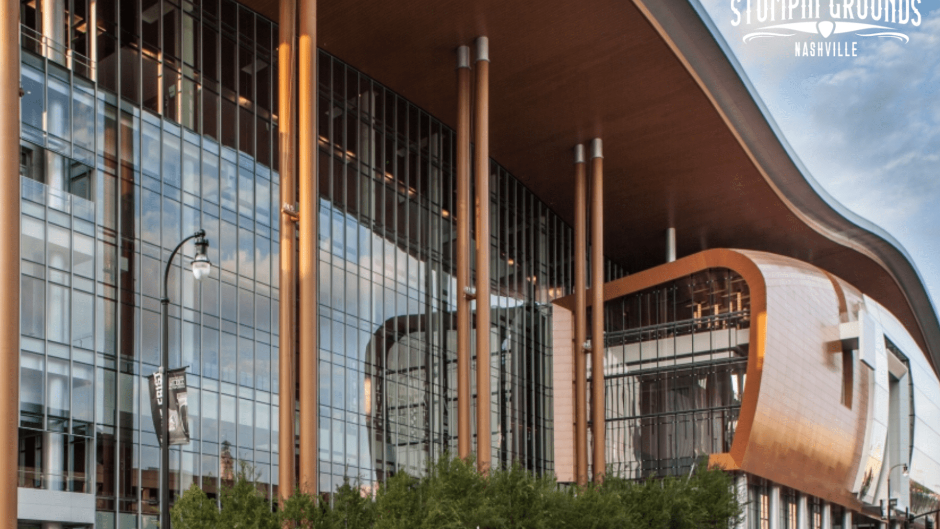 Modern glass building with wood accents, labeled Music City Center with Stompin Grounds Nashville logo.
