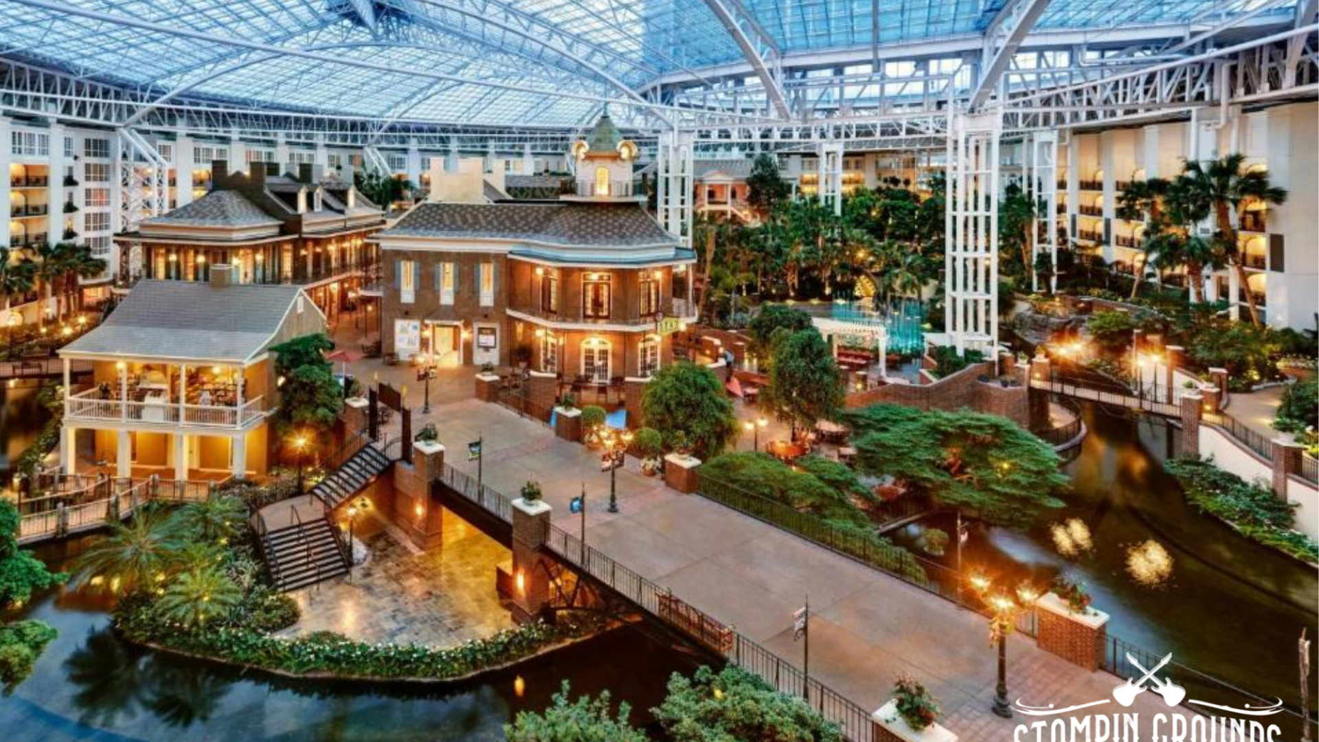 Indoor atrium with lush greenery, water features, and buildings under a glass roof at Gaylord Opryland Resort.